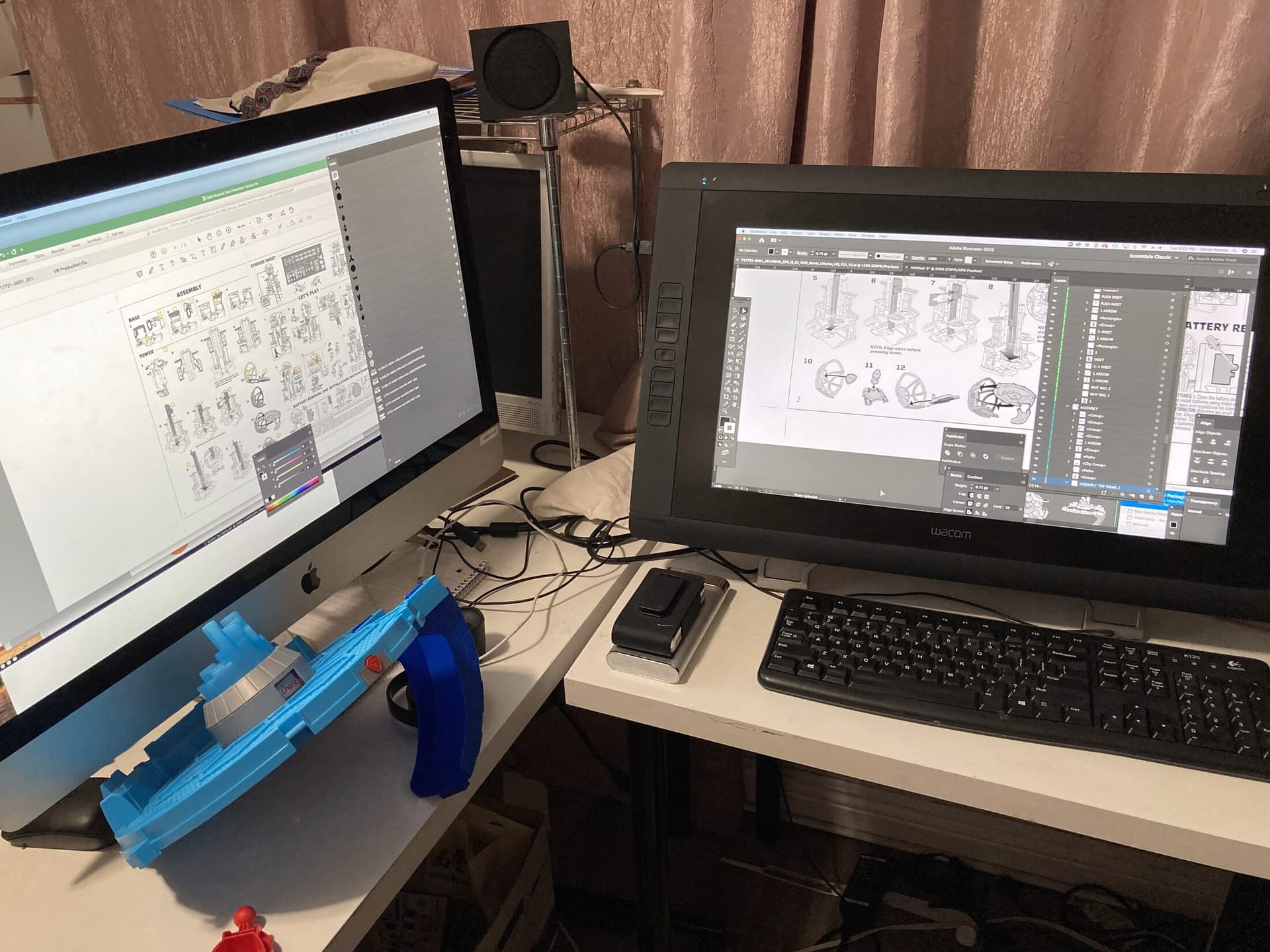 Dual-monitor production setup — line-art assembly instruction manual on one screen, Illustrator dieline work on the Wacom Cintiq